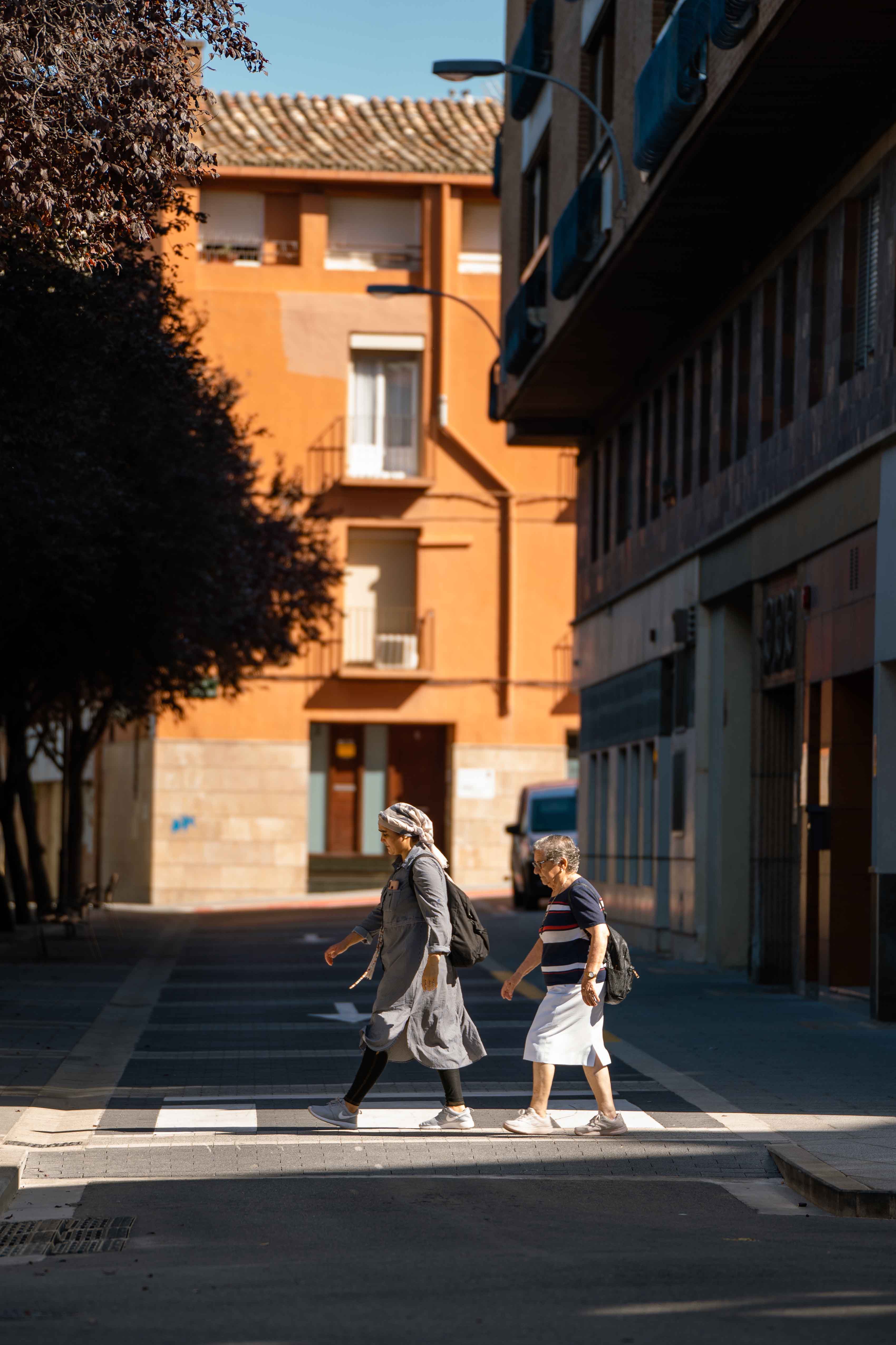 Peatones cruzando la calle remodelada con nueva iluminación y vegetación